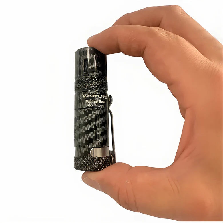 Hand holding a Vastlite flashlight with a checkered pattern on a white background