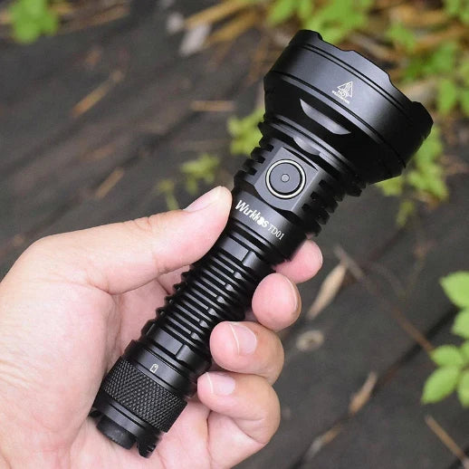 Black Wurkkos flashlight held in hand above forest floor