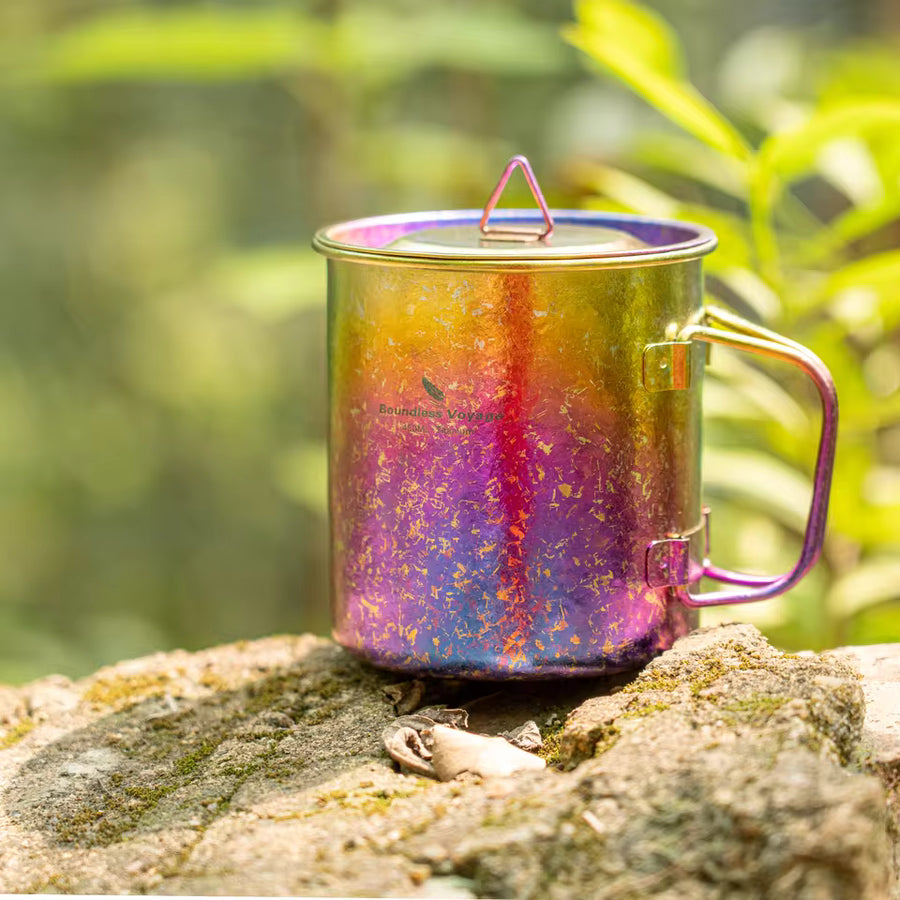 Multicolored mug with a lid on a rock against a natural background