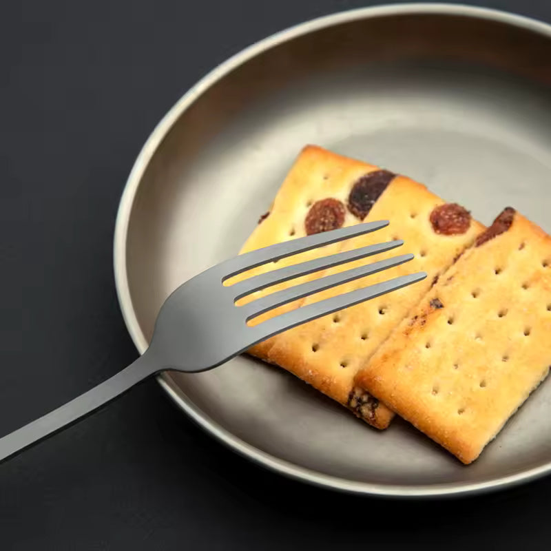 Two crackers with raisins on a plate with a fork beside them, on a dark background