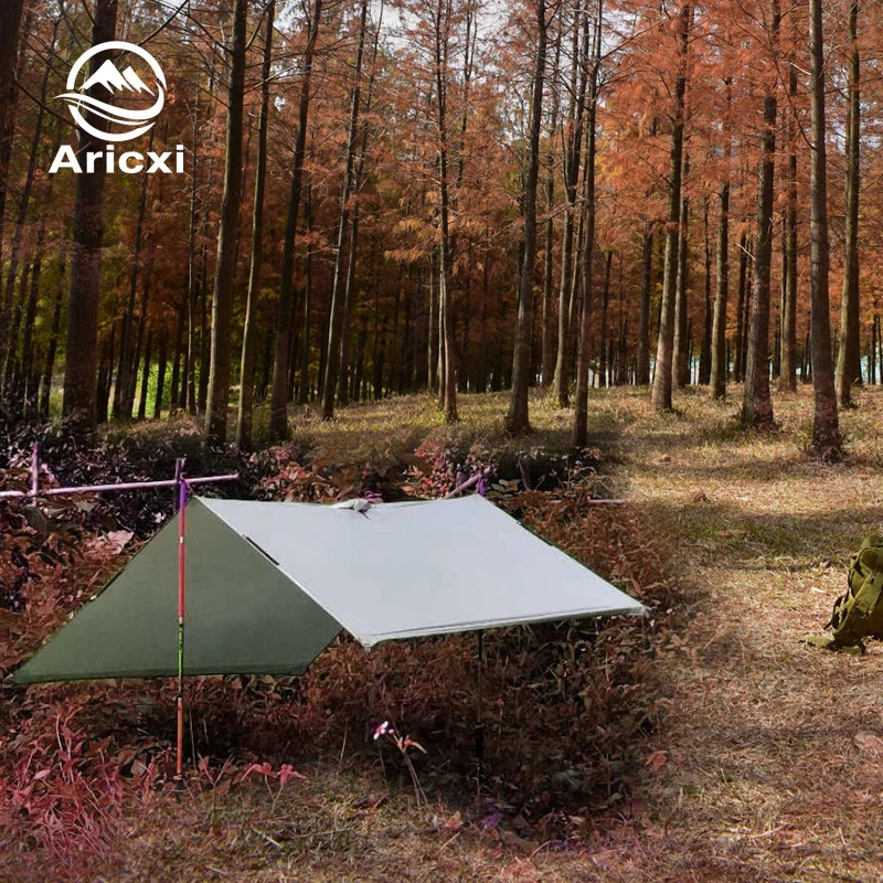 Camping tarp set up in a forest with Aricxi logo