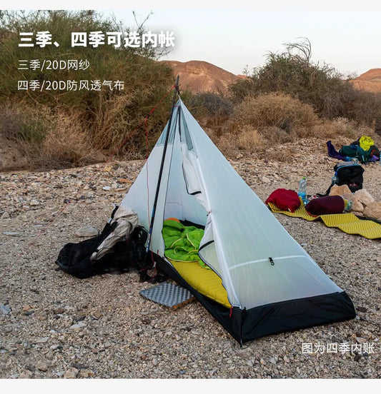 Single-person tent set up in a desert-like environment with camping gear around.