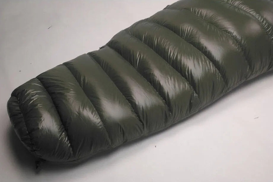 Rolled-up green sleeping bag on a gray background