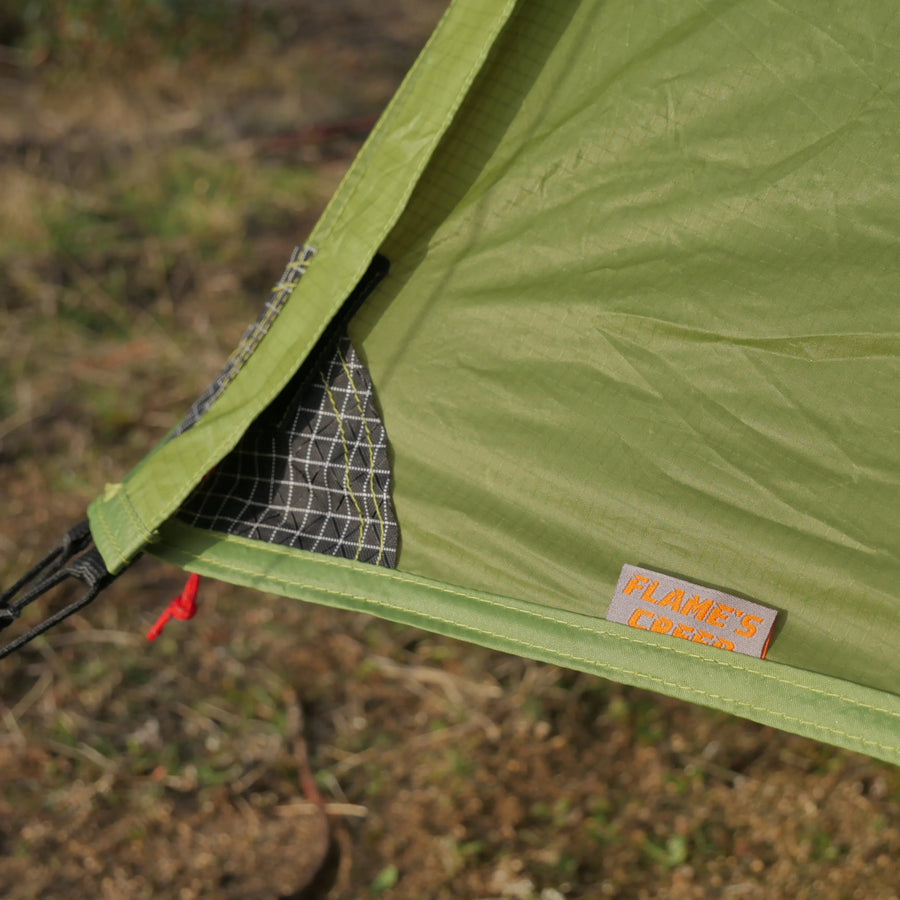 Close-up of a green tent with a brand label on a blurred natural background