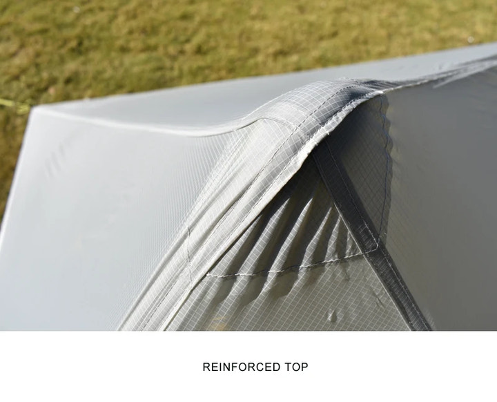 Close-up of a tent with a reinforced top section, grassy background.