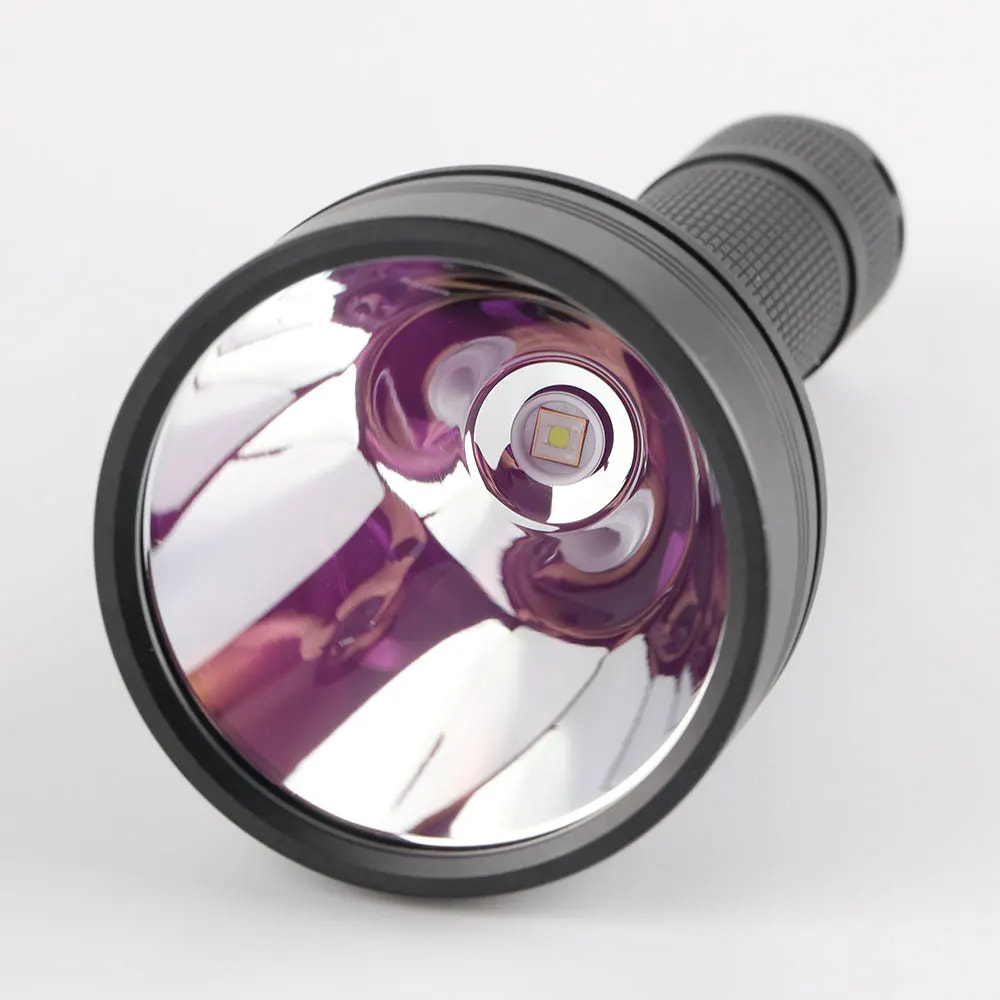Close-up of a flashlight lens with purple reflective coating on a white background