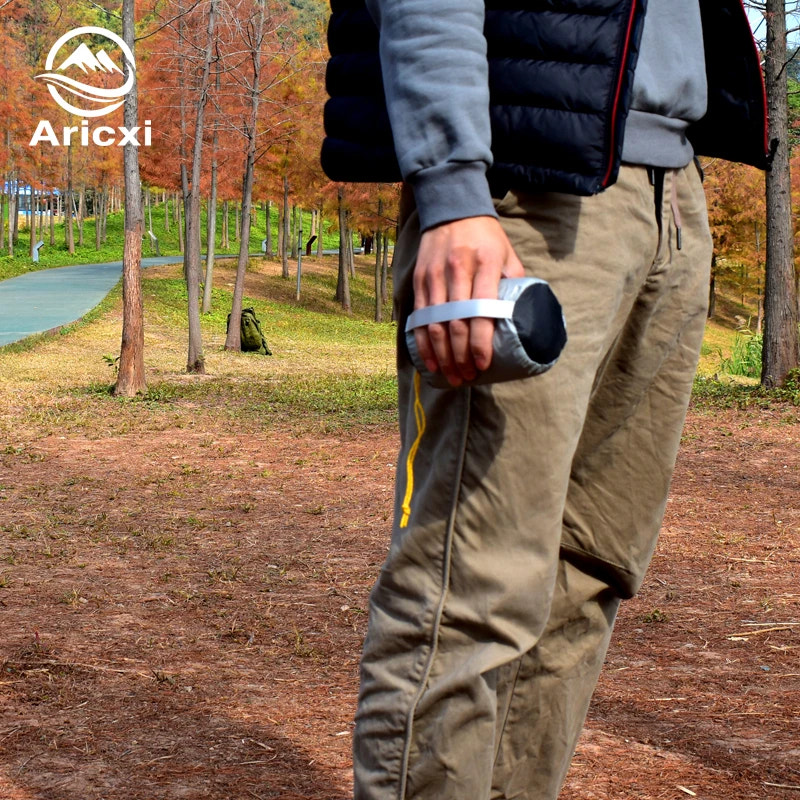 Person wearing a puffer jacket and cargo pants in a park setting with 'Aricxi' branding.