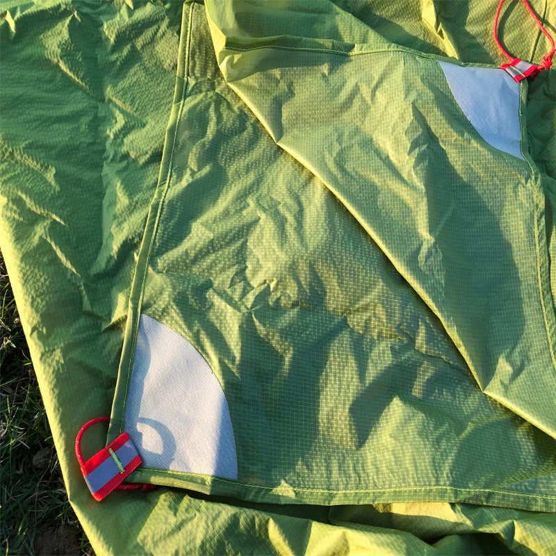 Green tent fabric with red and blue zipper pull on grass