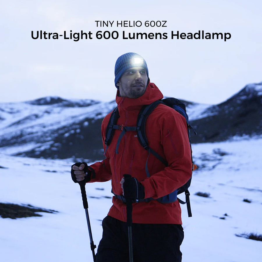 Person in red jacket with backpack and headlamp in snowy landscape, featuring Tiny Helio 600Z headlamp.