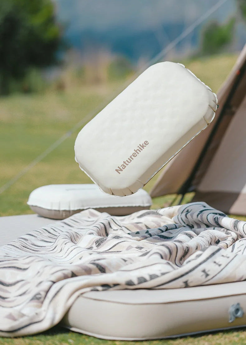 Inflatable camping mattress with pillow on a grassy outdoor setting