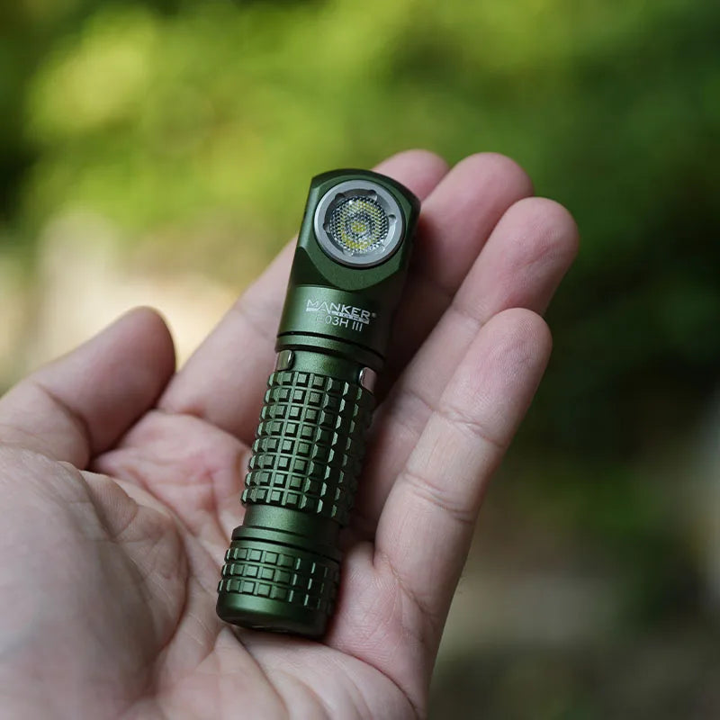 Green flashlight held in a hand with a blurred natural background