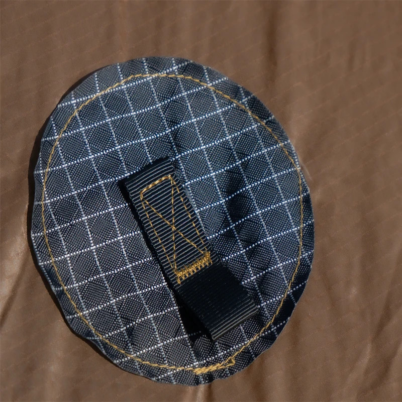 Black checkered fabric patch with a black strap on a brown background