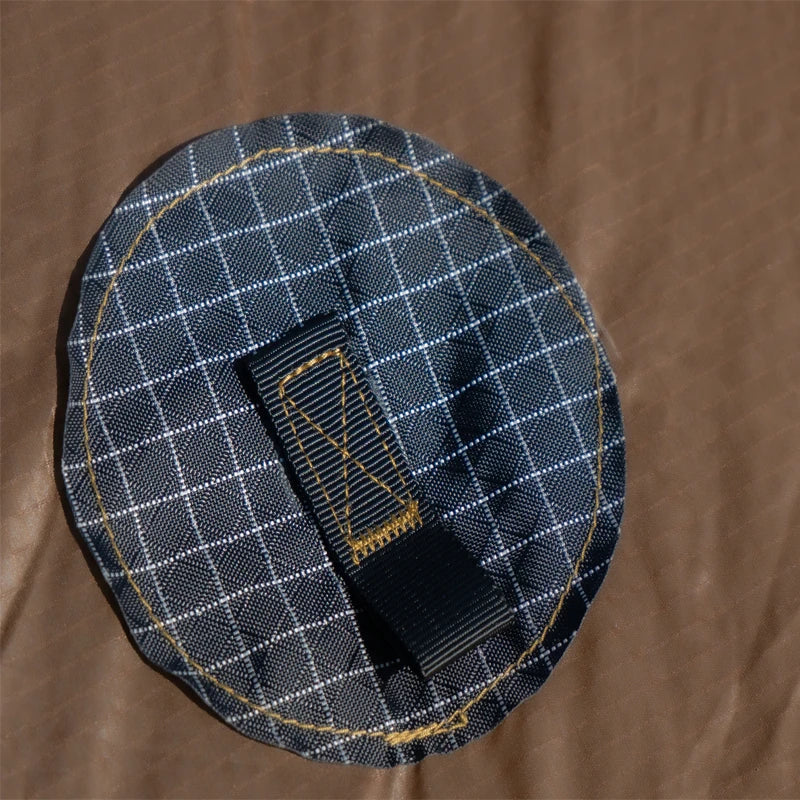 Black checkered fabric patch with a black strap on a brown background