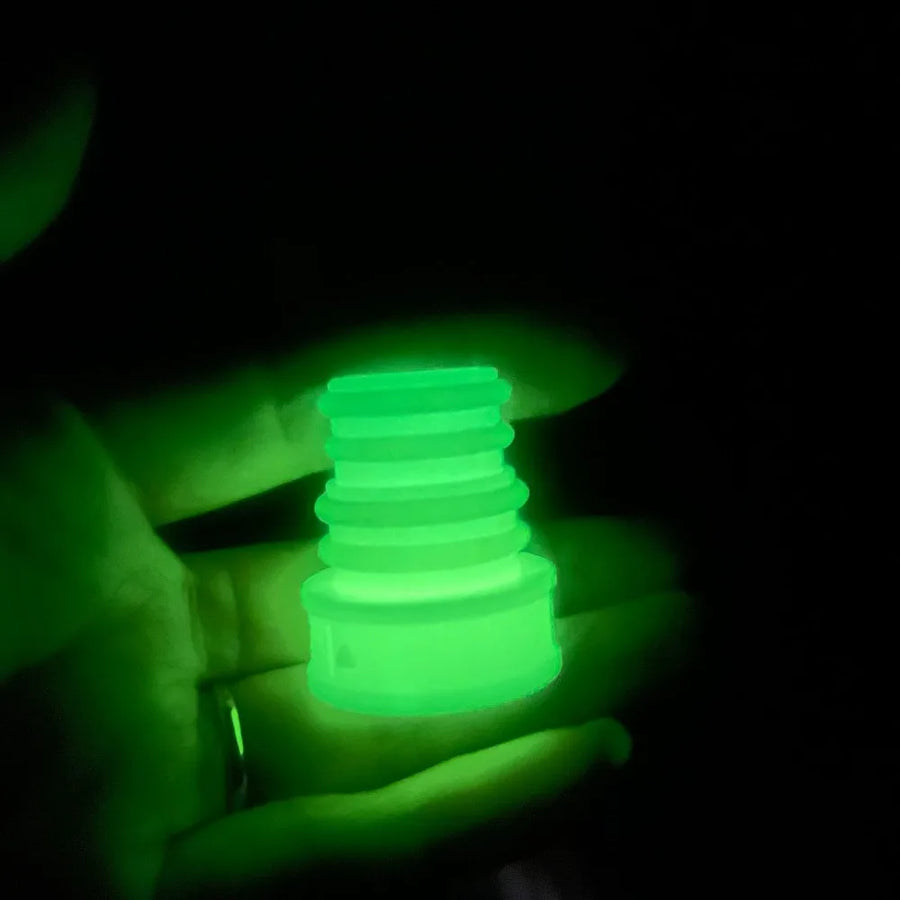 Glowing green object held in a hand against a dark background