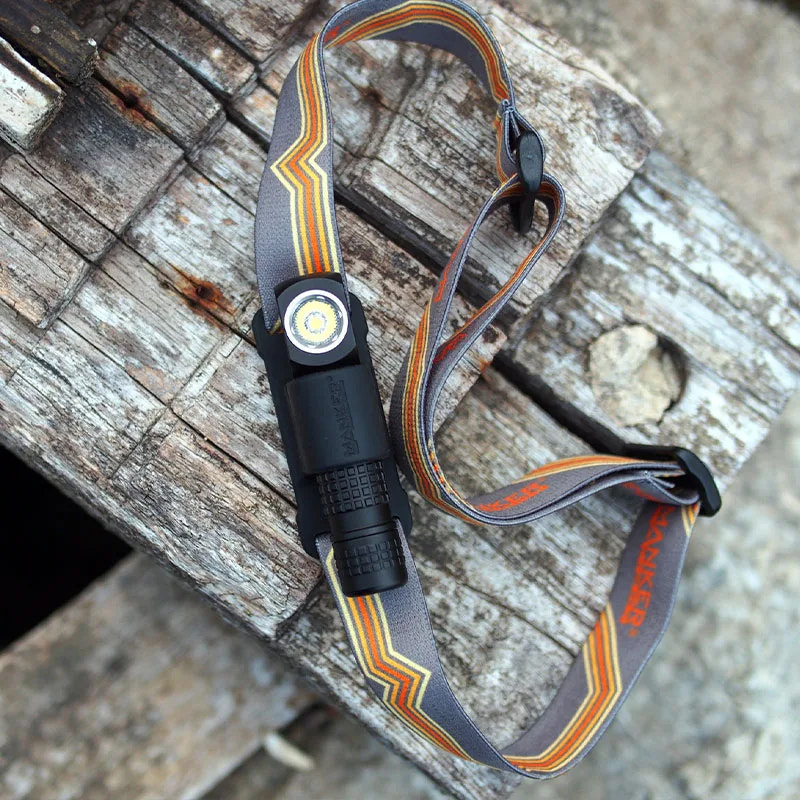 Black headlamp with gray strap on a wooden surface