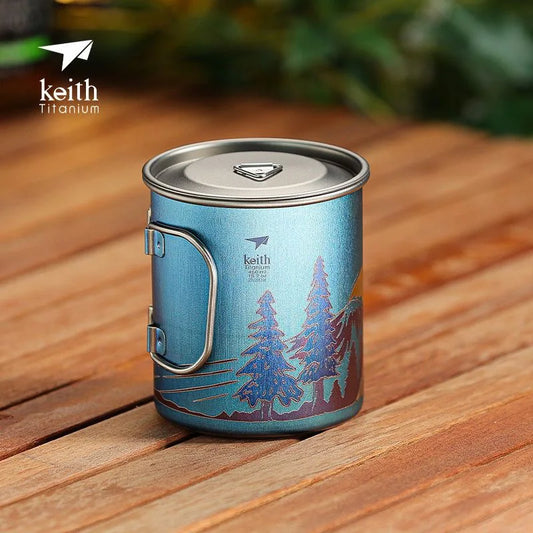 Blue camping mug with tree design on a wooden surface, featuring the Keith Titanium brand.