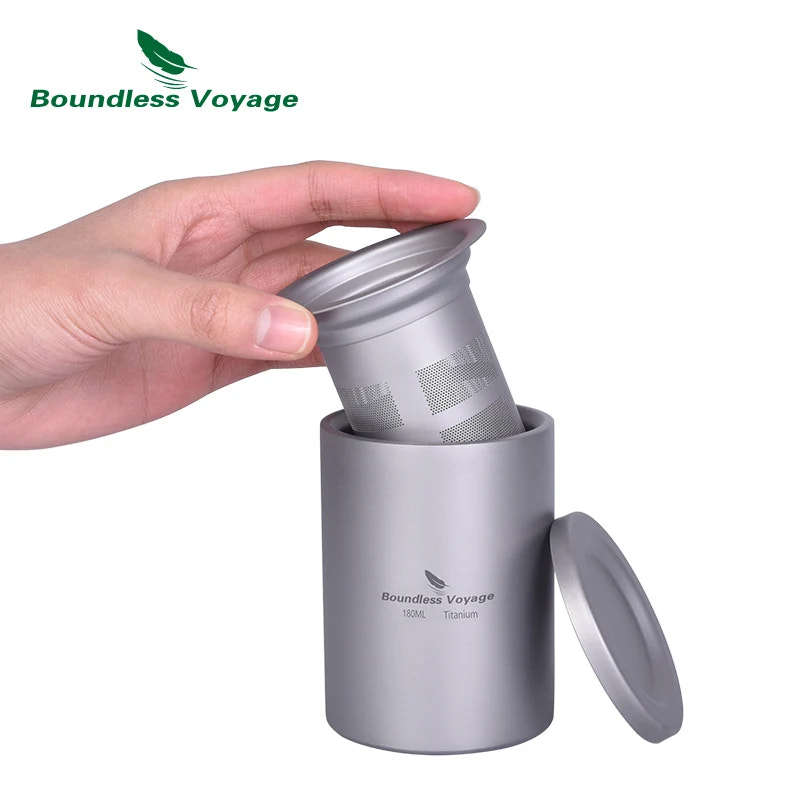 Hand holding a titanium travel mug with filter against a white background, featuring 'Boundless Voyage' brand.
