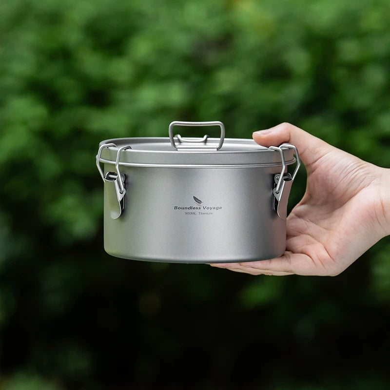 Hand holding a small metal pot with a blurred green background