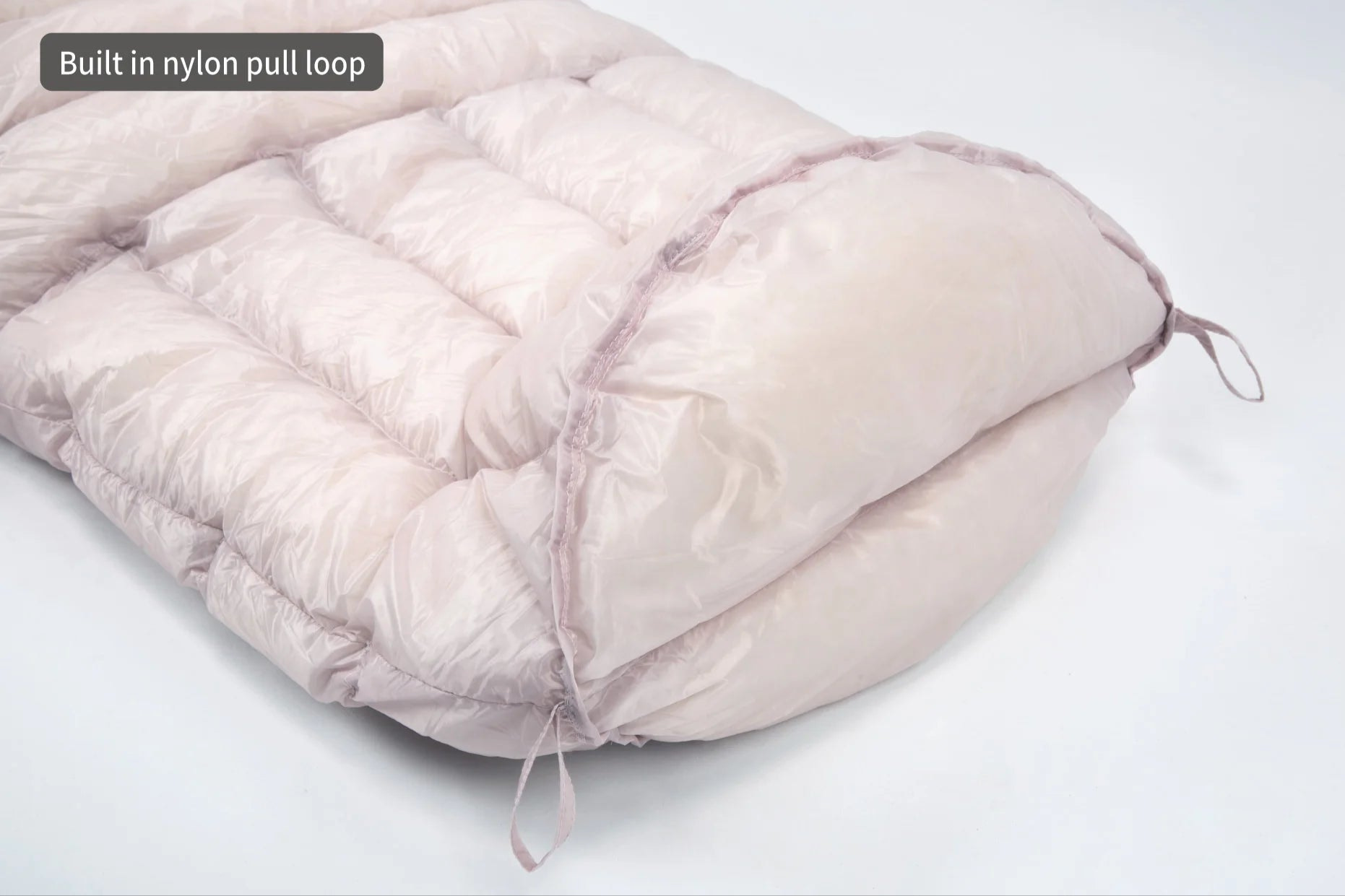 Pink sleeping bag with a built-in nylon pull loop on a white background