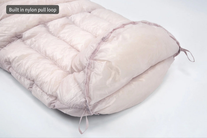 Pink sleeping bag with a built-in nylon pull loop on a white background