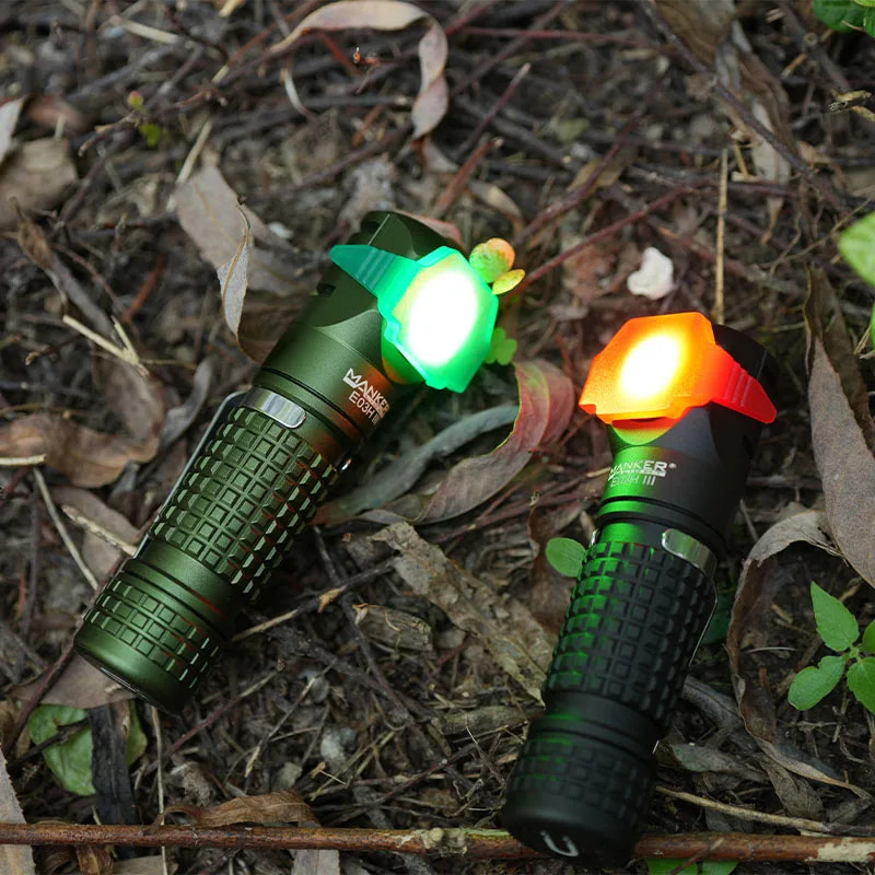 Two flashlights with green and orange lights on a natural background