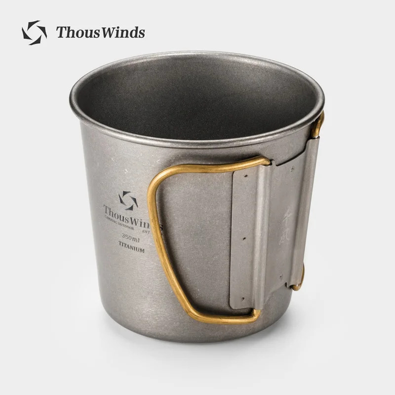 Metal mug with gold handle on a white background, branded 'ThousWinds'.