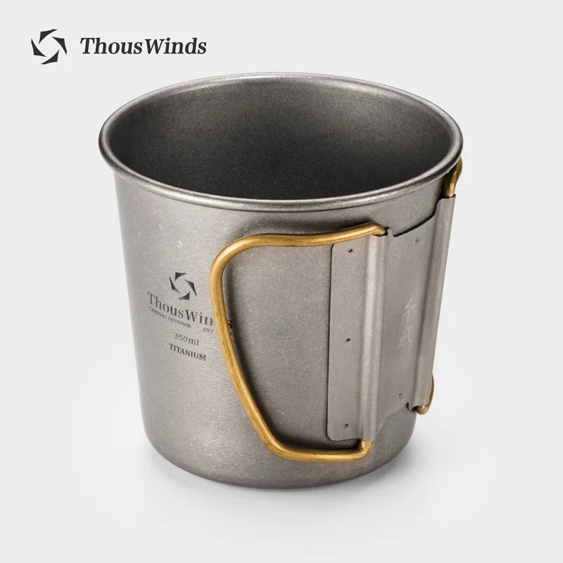 Metal mug with gold handle on a white background, branded 'ThousWinds'.