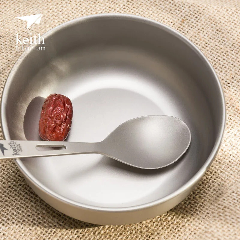titanium bowl with spoon and date on a textured beige background, featuring the Keith Titanium logo.