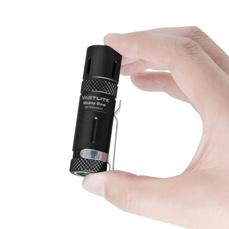 Hand holding a Vastlite Minima Bow flashlight against a white background