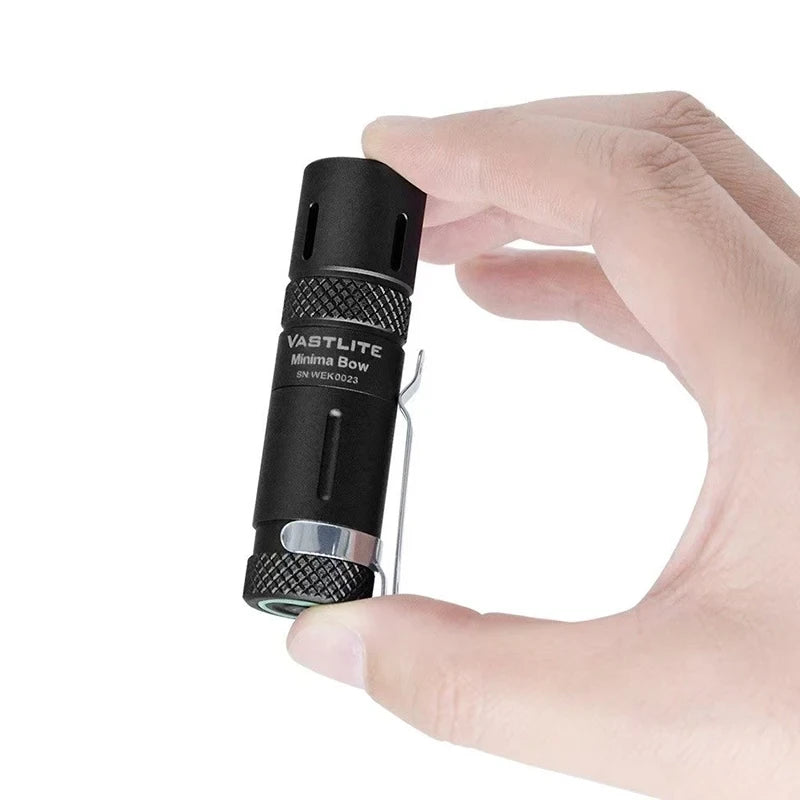 Hand holding a Vastlite Minima Bow flashlight against a white background