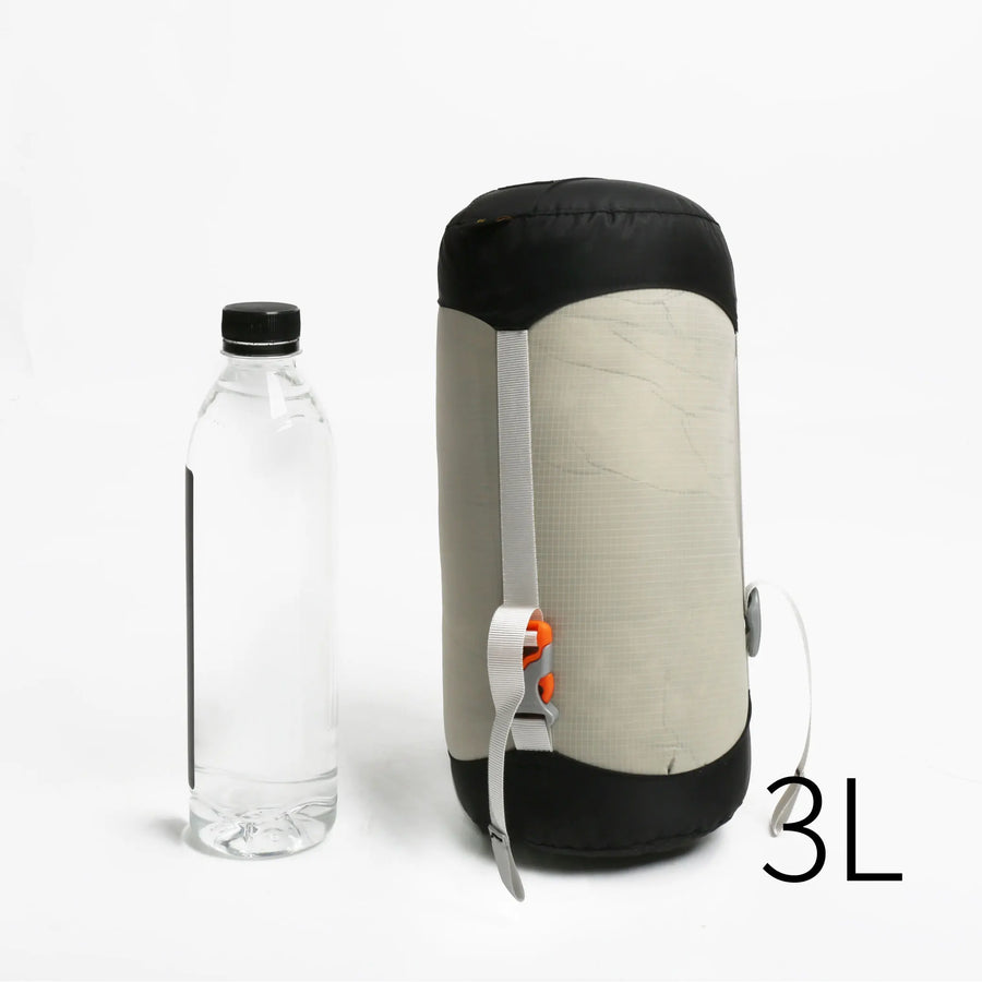 3L sleeping pad compression sac next to a clear bottle on a white background