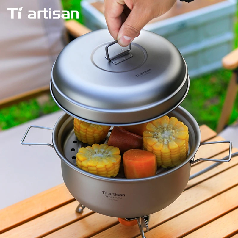 Portable outdoor cooking pot with steamed corn and carrots on a wooden surface, featuring Tiartisan branding.