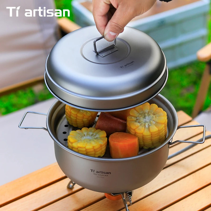 Portable outdoor cooking pot with steamed corn and carrots on a wooden surface, featuring Tiartisan branding.