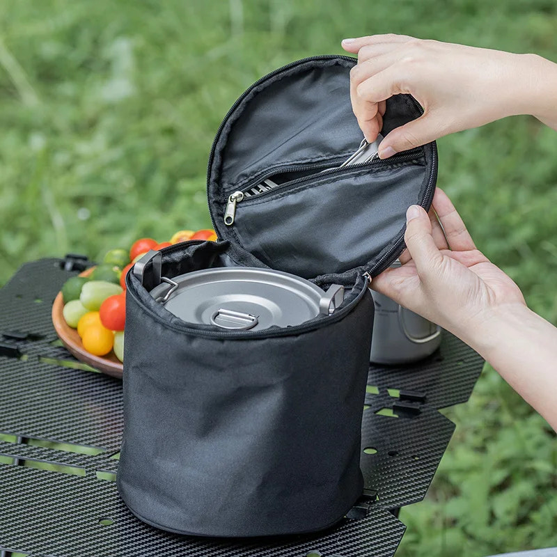 Person opening a black bag with a picnic setup in the background