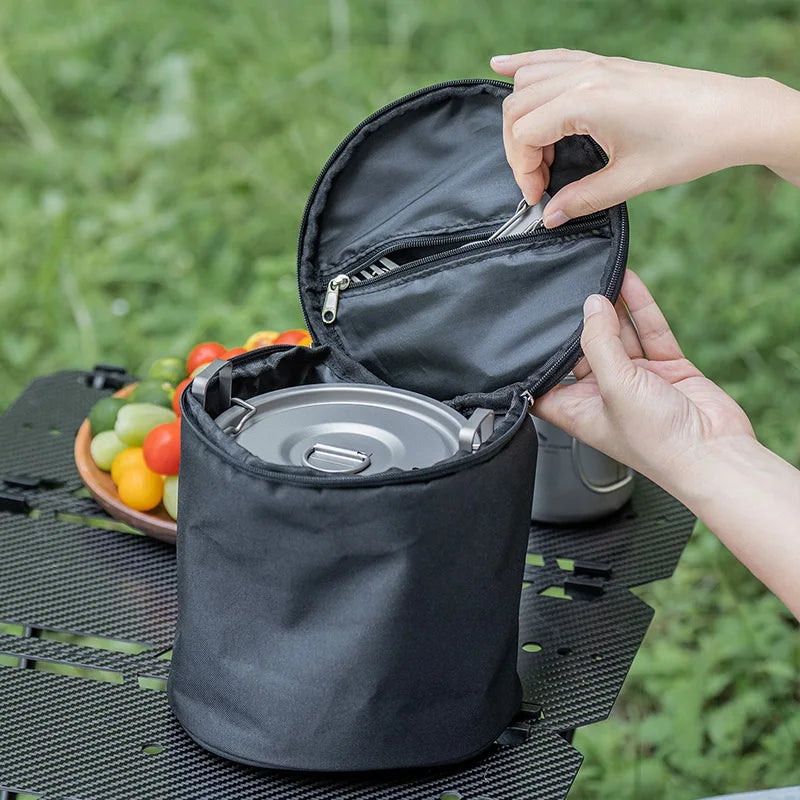 Person opening a black bag with a picnic setup in the background