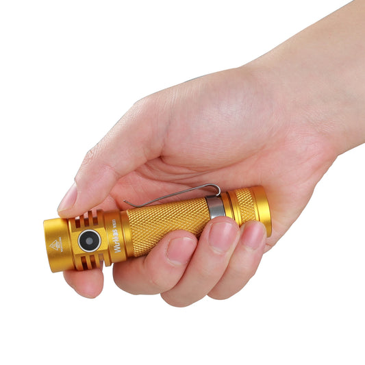 Gold flashlight held in a hand against a white background