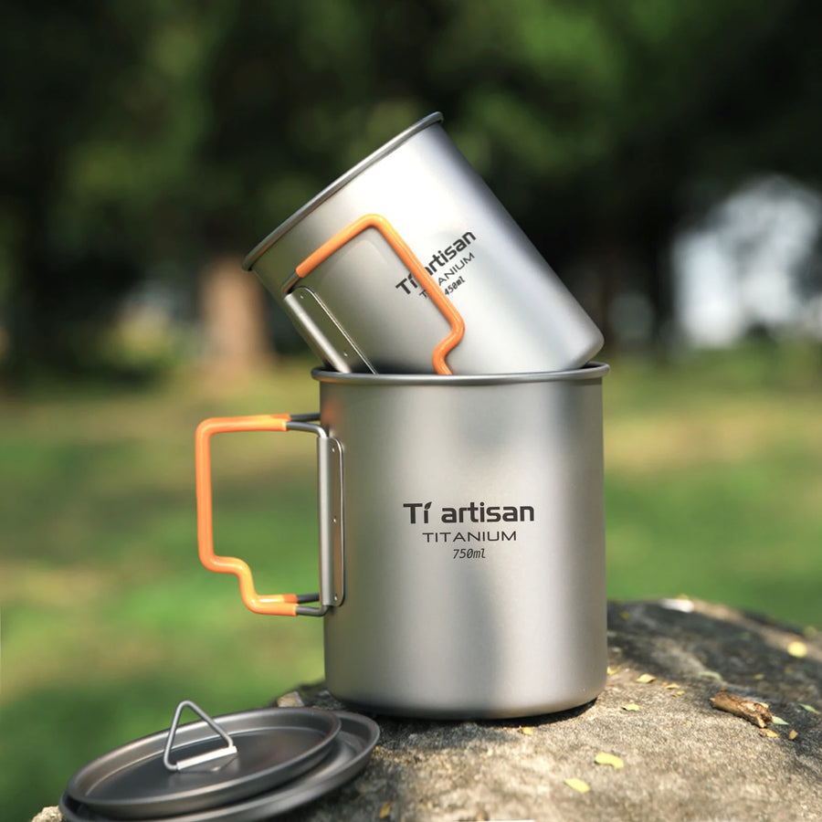 Two Tiartisan titanium mugs stacked on a rock with a blurred natural background