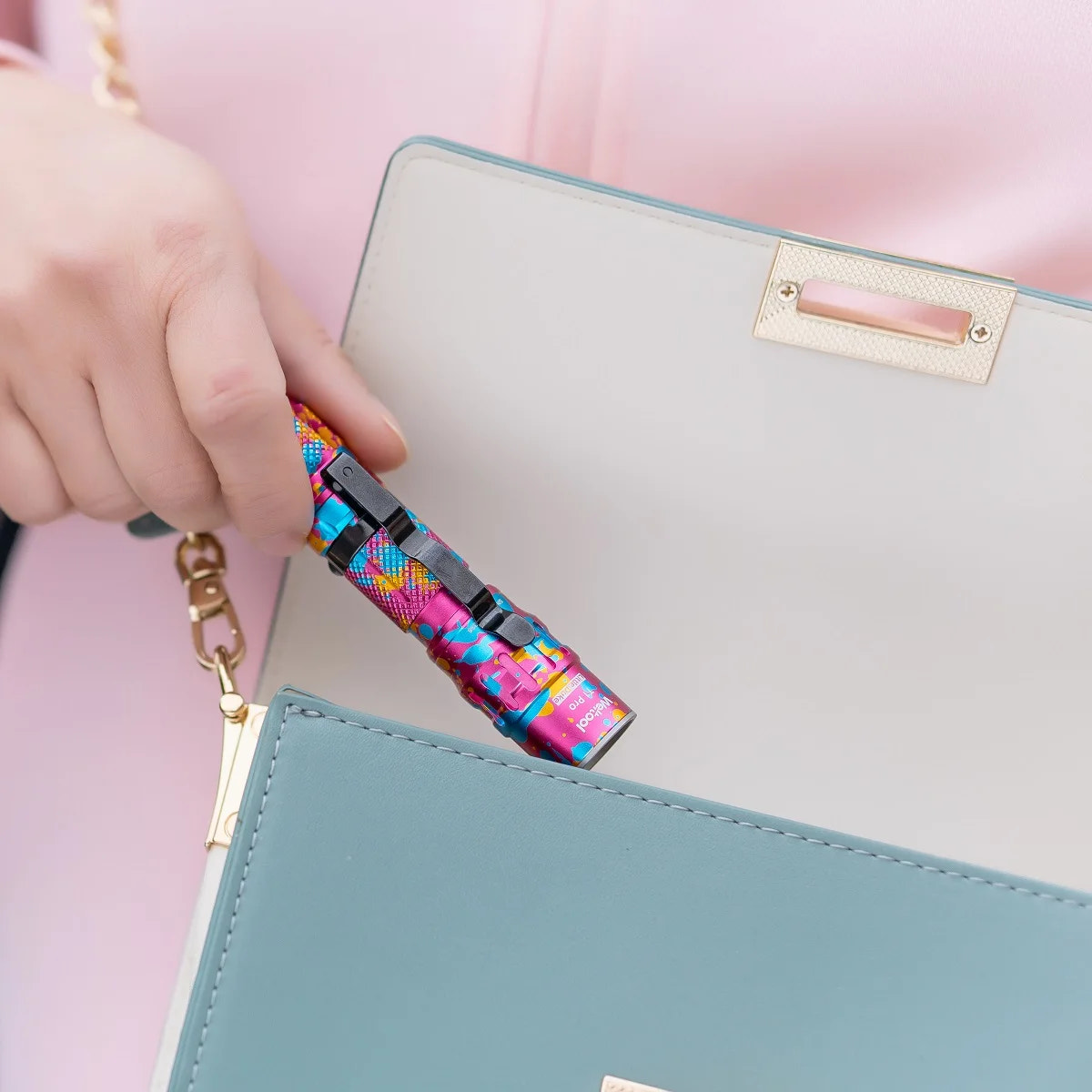 Colorful torch and a light blue handbag with a pink background