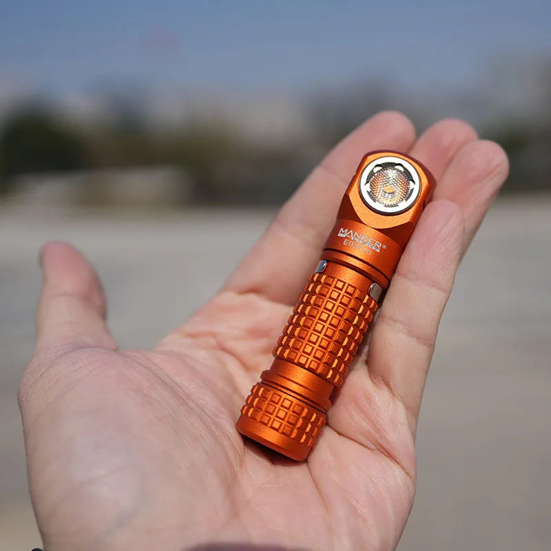 Orange flashlight held in a hand with a blurred outdoor background