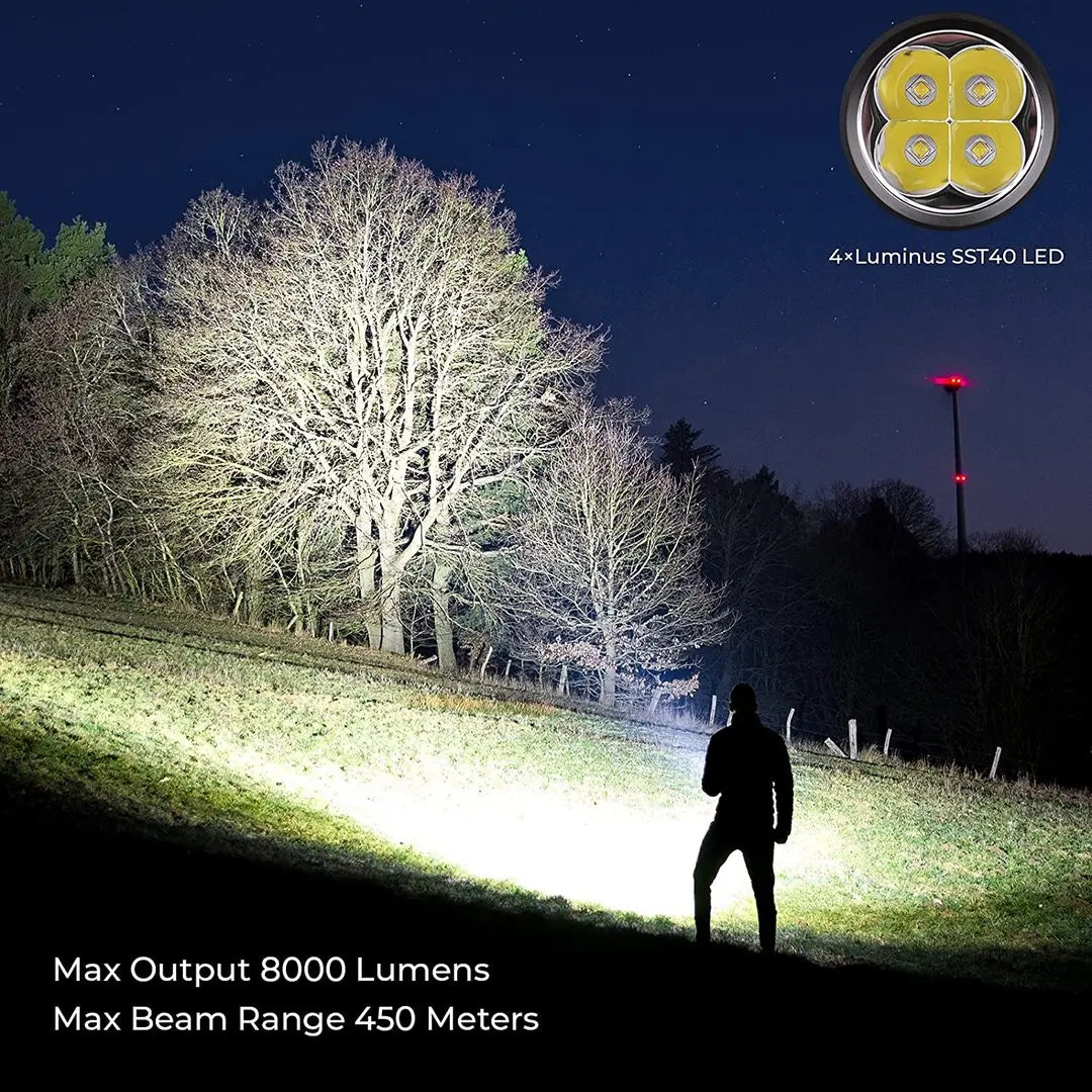 Person using a high-powered flashlight in a dark outdoor setting with tree silhouettes.