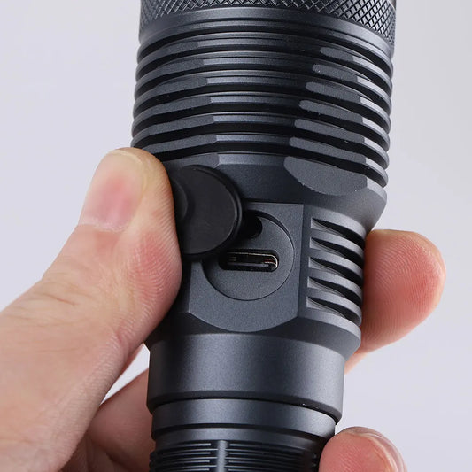 Close-up of a person holding a black flashlight with a white background