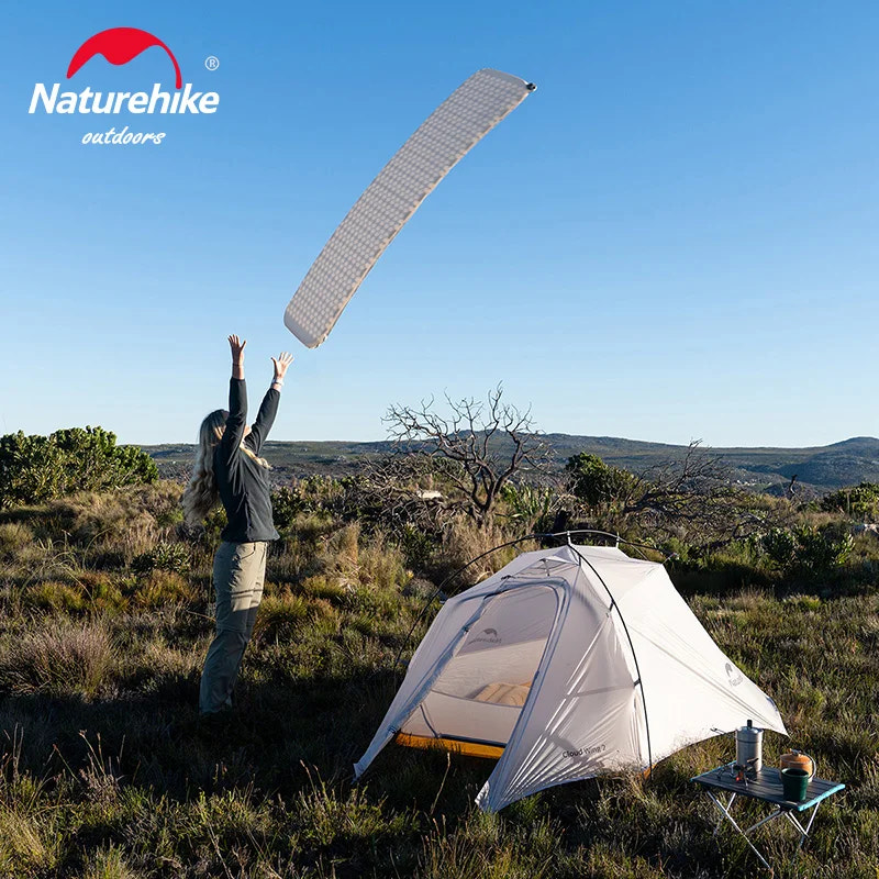 Person setting up a tent with a sleeping pad in an outdoor setting, featuring the Naturehike brand.
