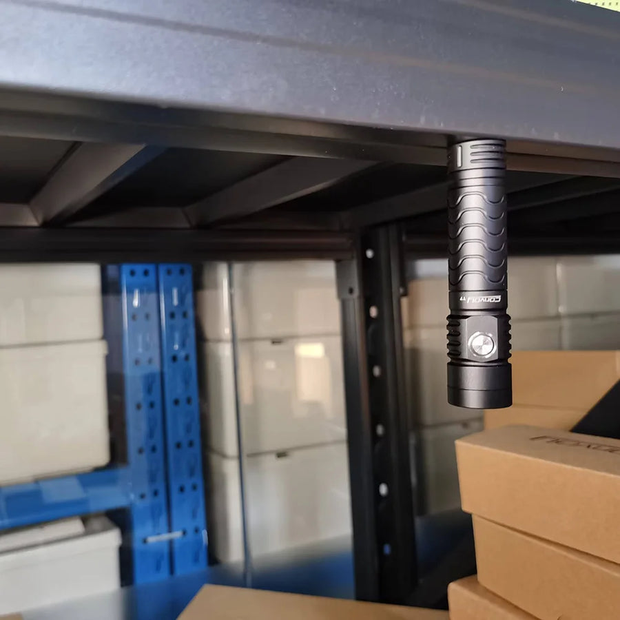 Black flashlight hanging from a shelf in a storage area with boxes and shelves.