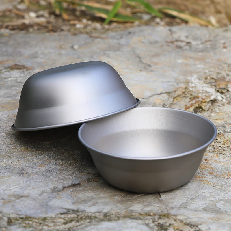 Two gray metal bowls on a stone surface