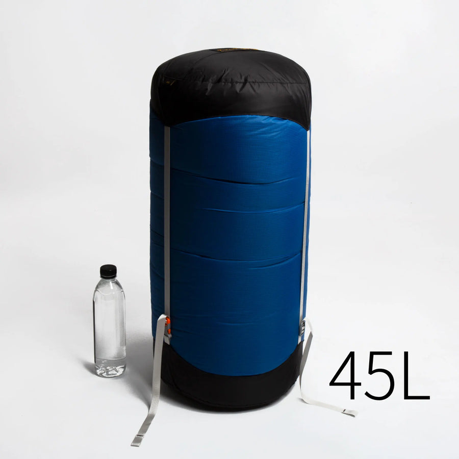 Blue and black compression bag with a water bottle for scale on a white background