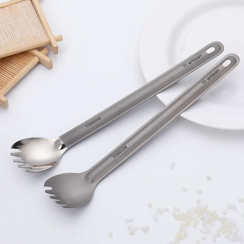 Two titanium Spork utensils on a white surface with a blurred background