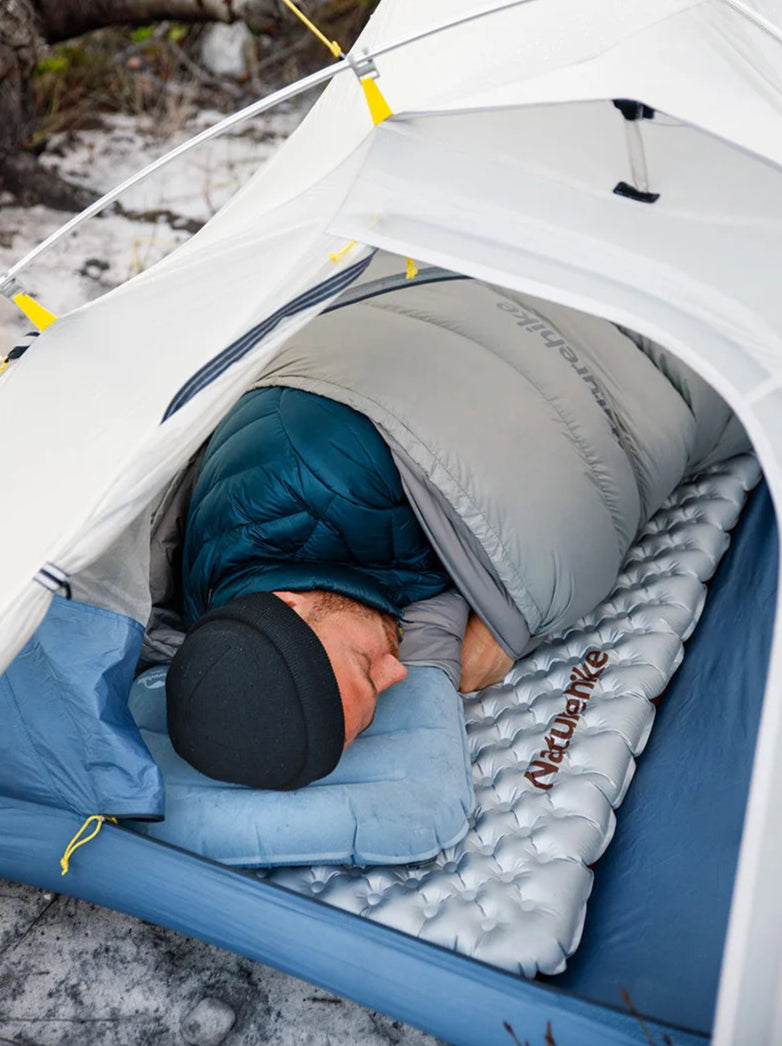 Person sleeping in a tent with a sleeping pad on a snowy ground