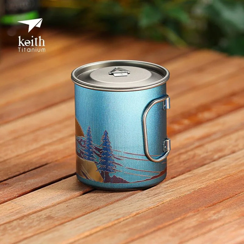 Blue camping mug with nature design on a wooden surface, featuring the Keith Titanium brand.