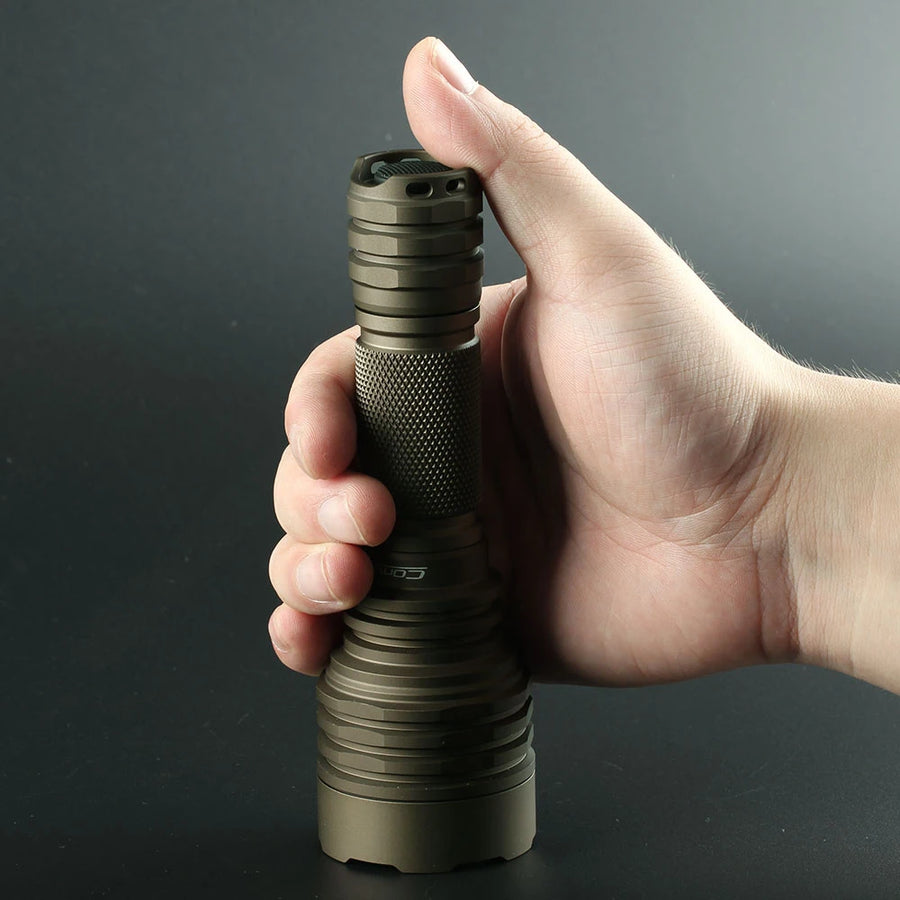 Hand holding a tactical flashlight against a dark background