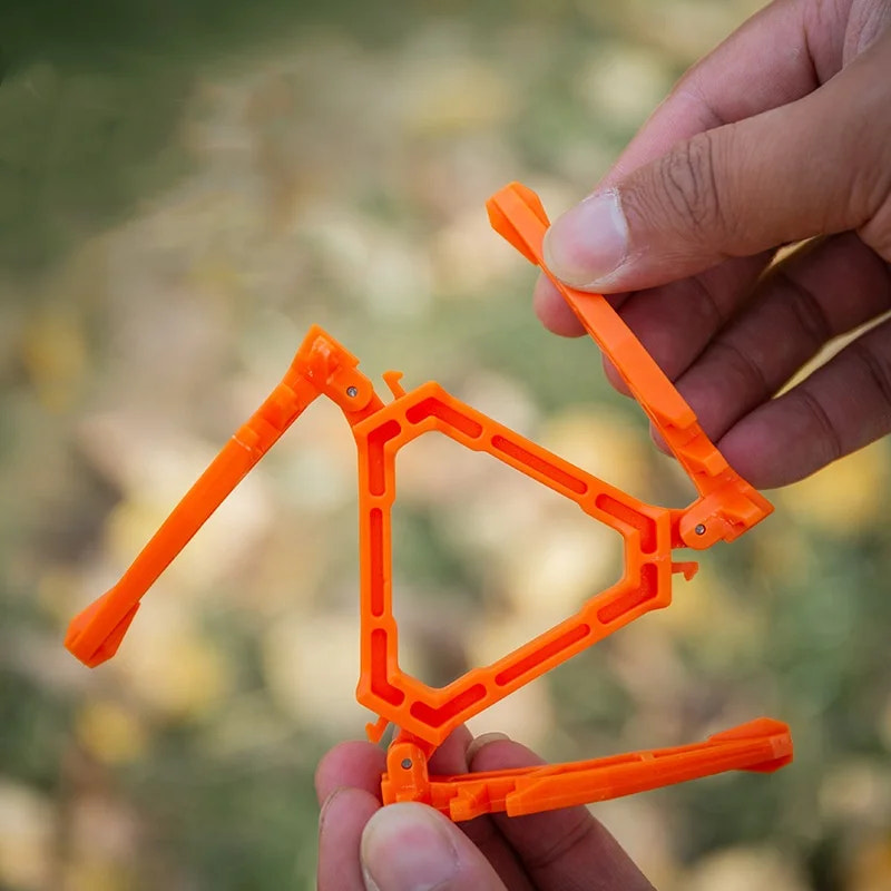 Orange metal frame held by a hand with a blurred natural background